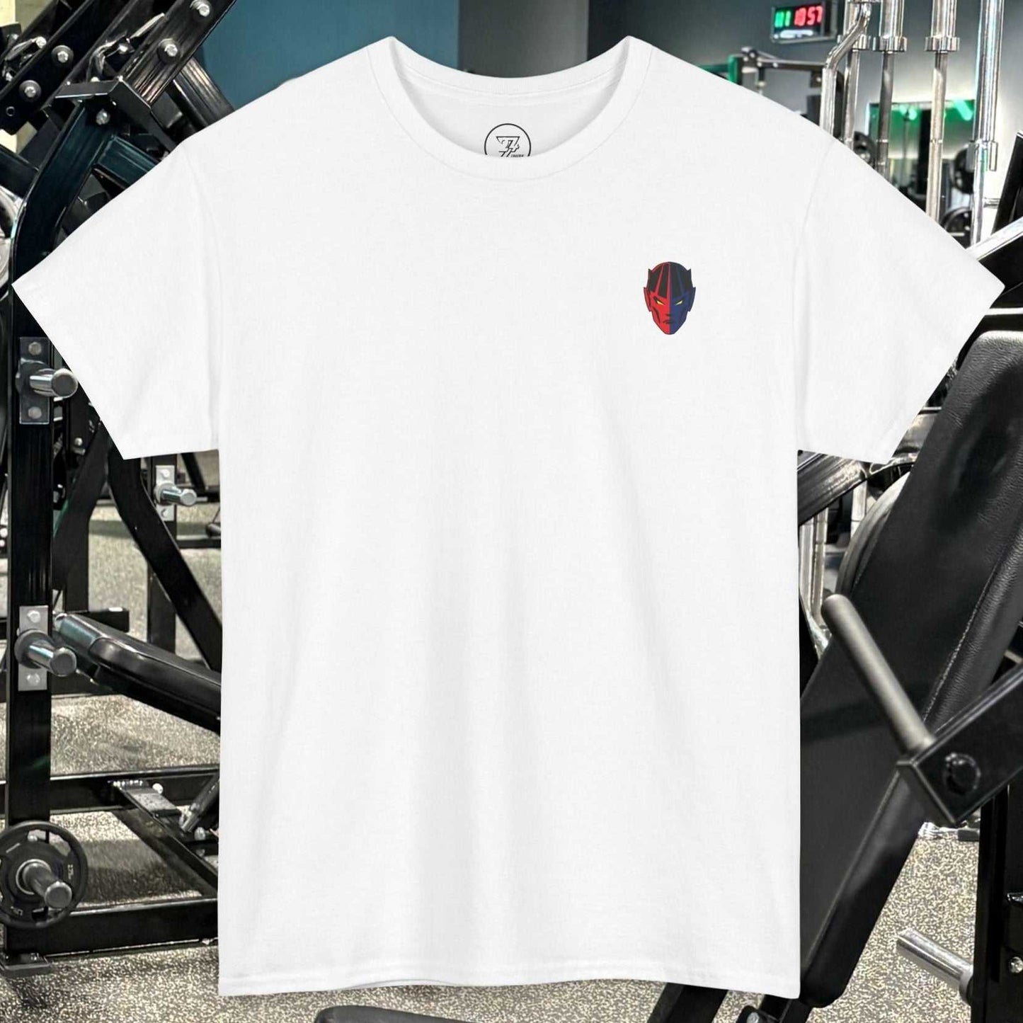 White bodybuilding tee with small red and black comic-style fitness character graphic on chest, displayed in gym setting