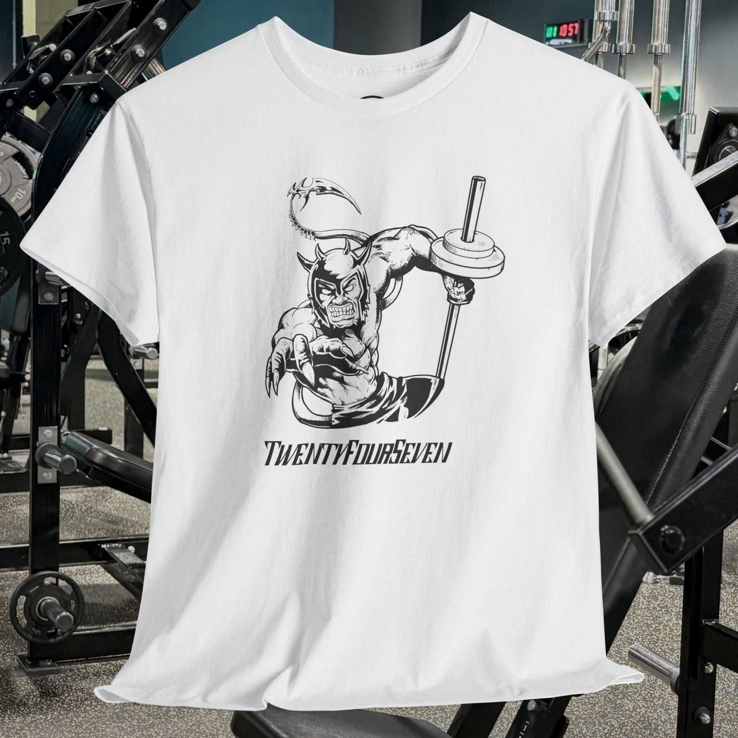 White gym tee with hand-drawn comic-style illustration of a muscular superhero lifting a barbell, displayed in a gym setting