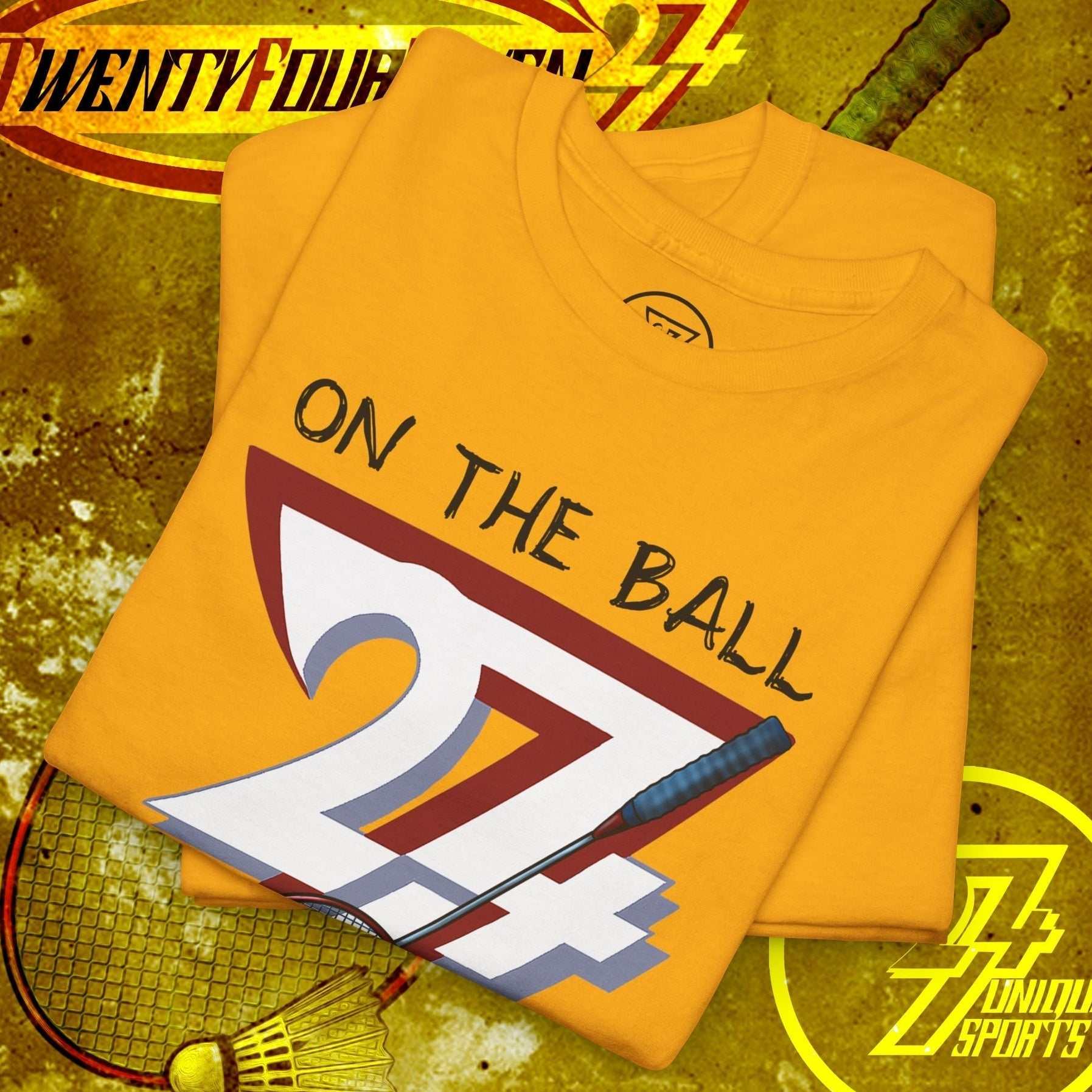 Yellow badminton tee with hand-drawn "On The Ball 24/7" graphic, placed on a textured sports background featuring shuttlecock and racket