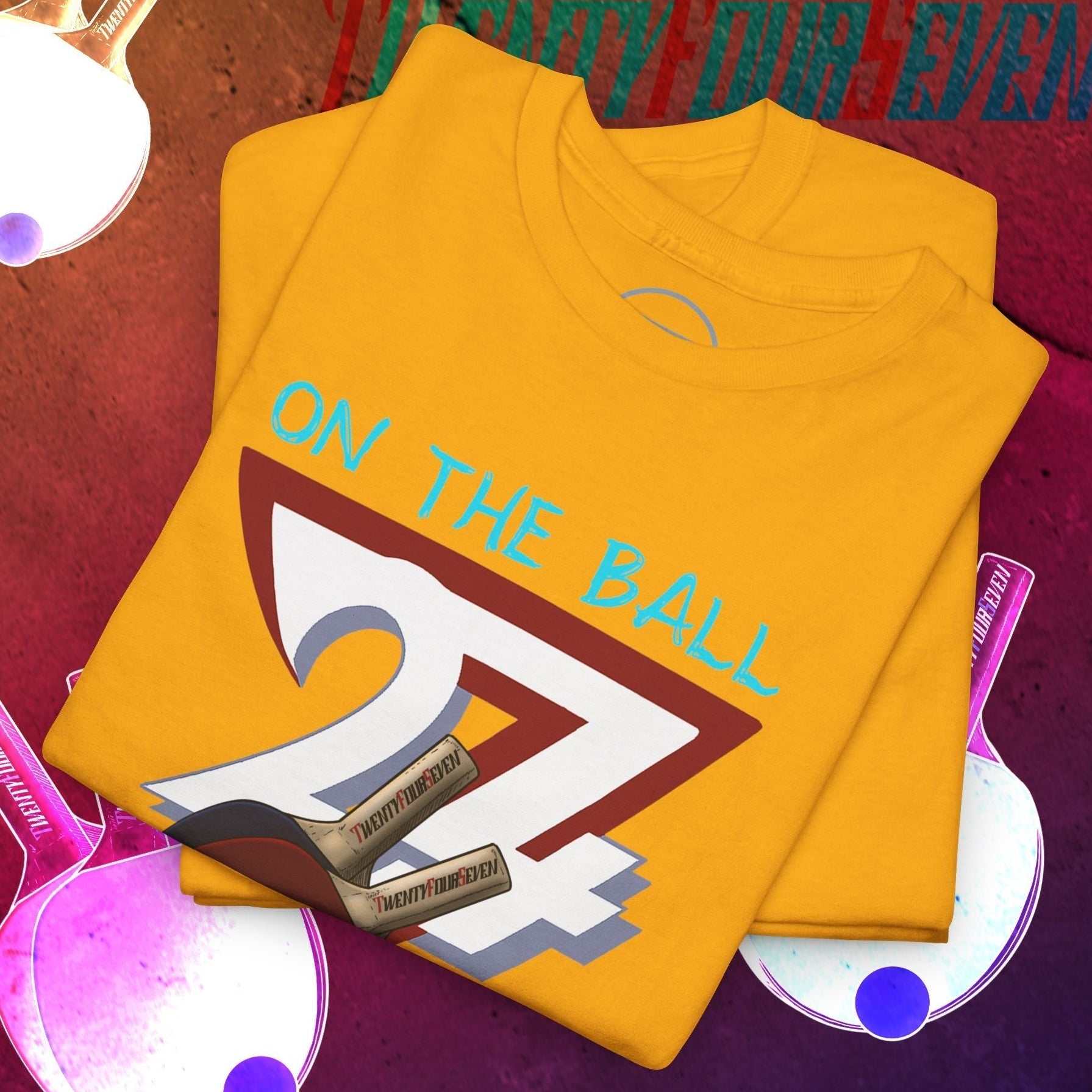 Yellow ping-pong t-shirt with hand-drawn illustration and "On The Ball" text, styled for sports and casual wear