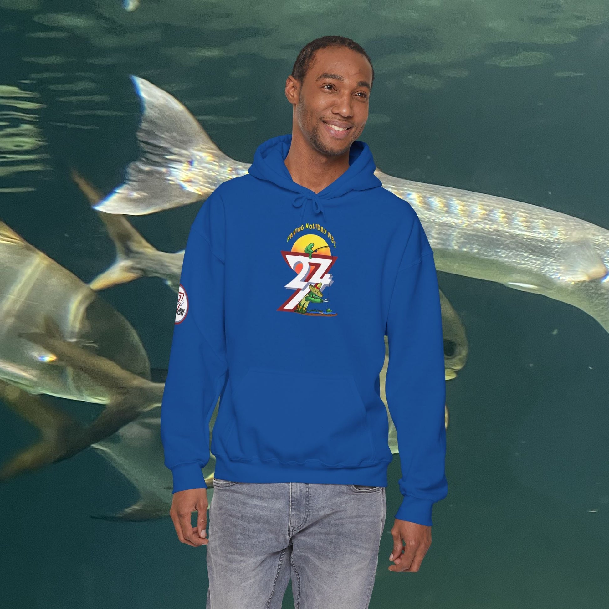 man wearing blue funny fishing hoodie with cactus design standing in front of aquarium fish background