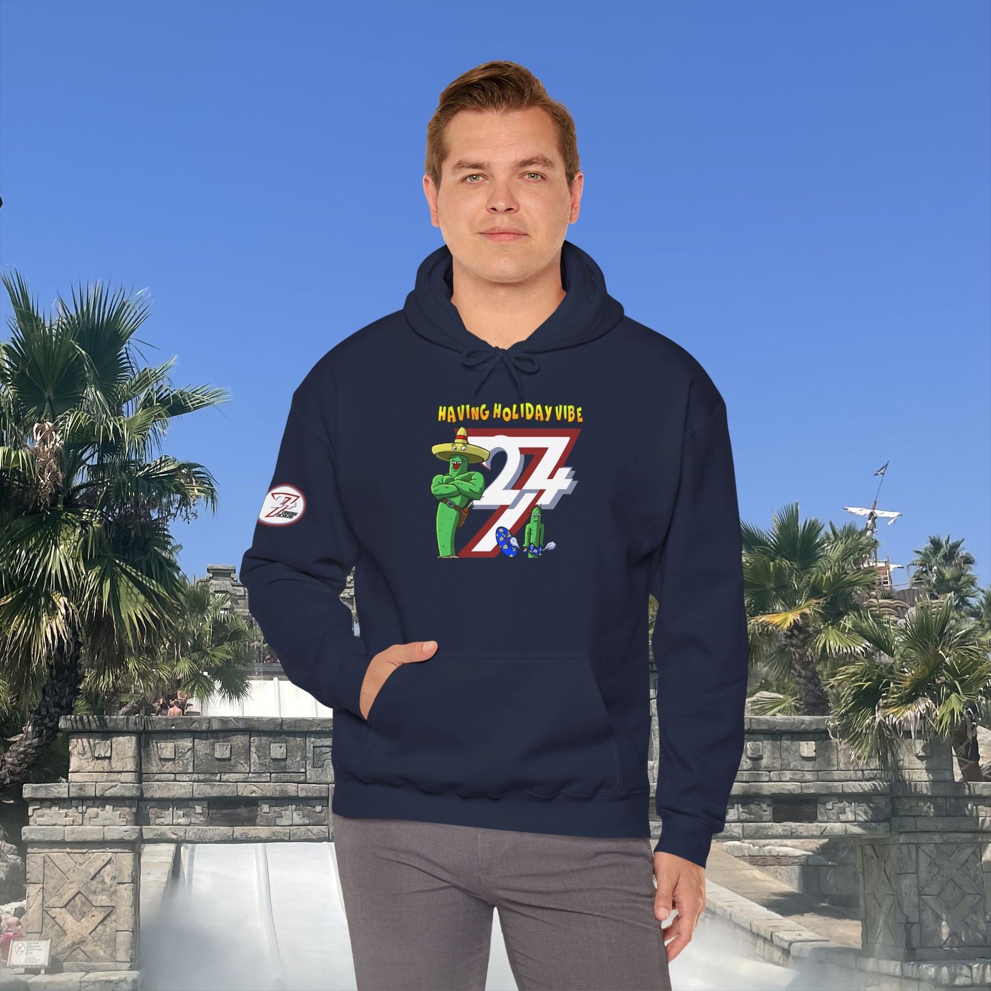 man wearing navy cactus hoodie with cartoon holiday design and kangaroo pocket outdoors on sunny day
