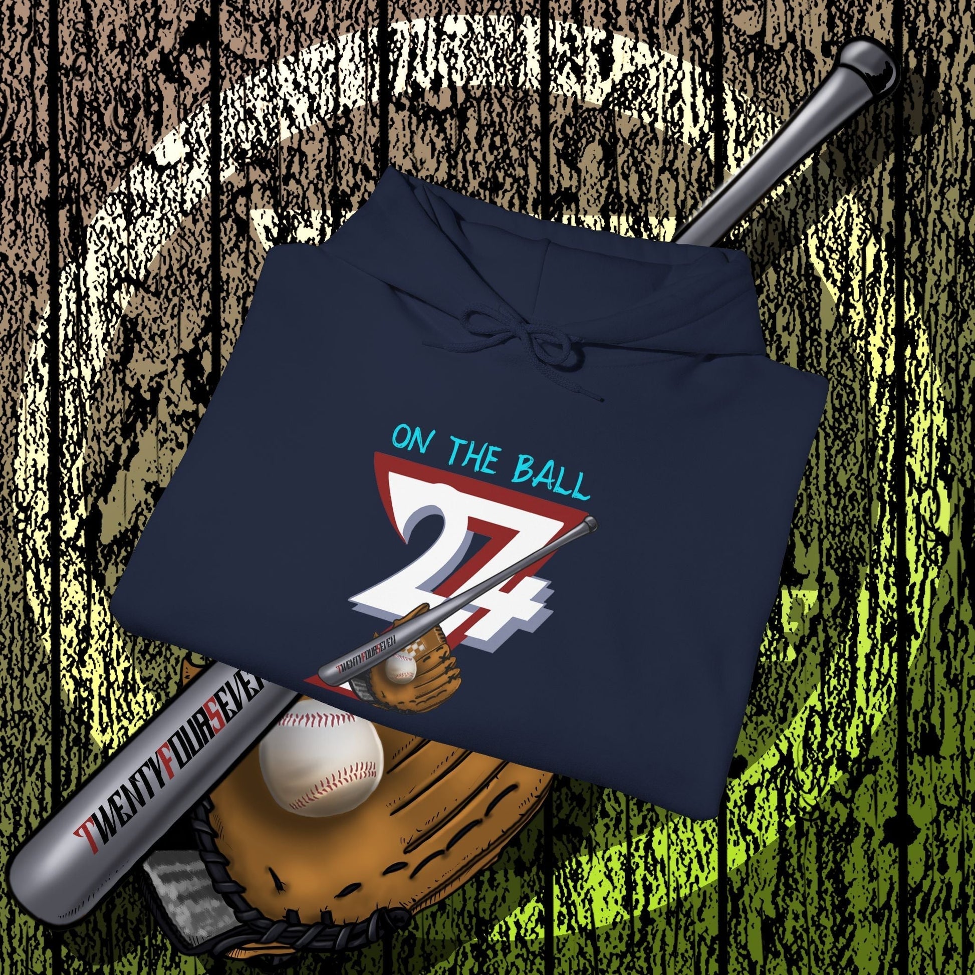 navy blue baseball hoodie with "On The Ball 24/7" graphic, folded with baseball bat, ball, and glove on wooden background
