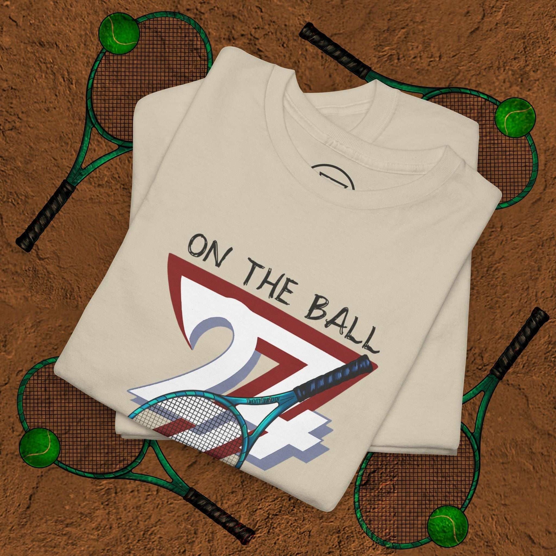tennis tee with hand-drawn "On the Ball 24/7" design featuring a tennis racket on beige fabric
